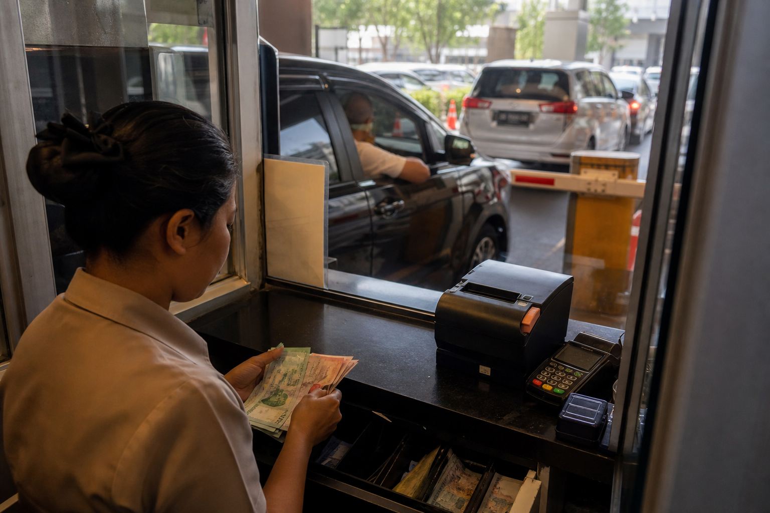 Petugas di loket keluar parkir merapikan pembayaran tiket